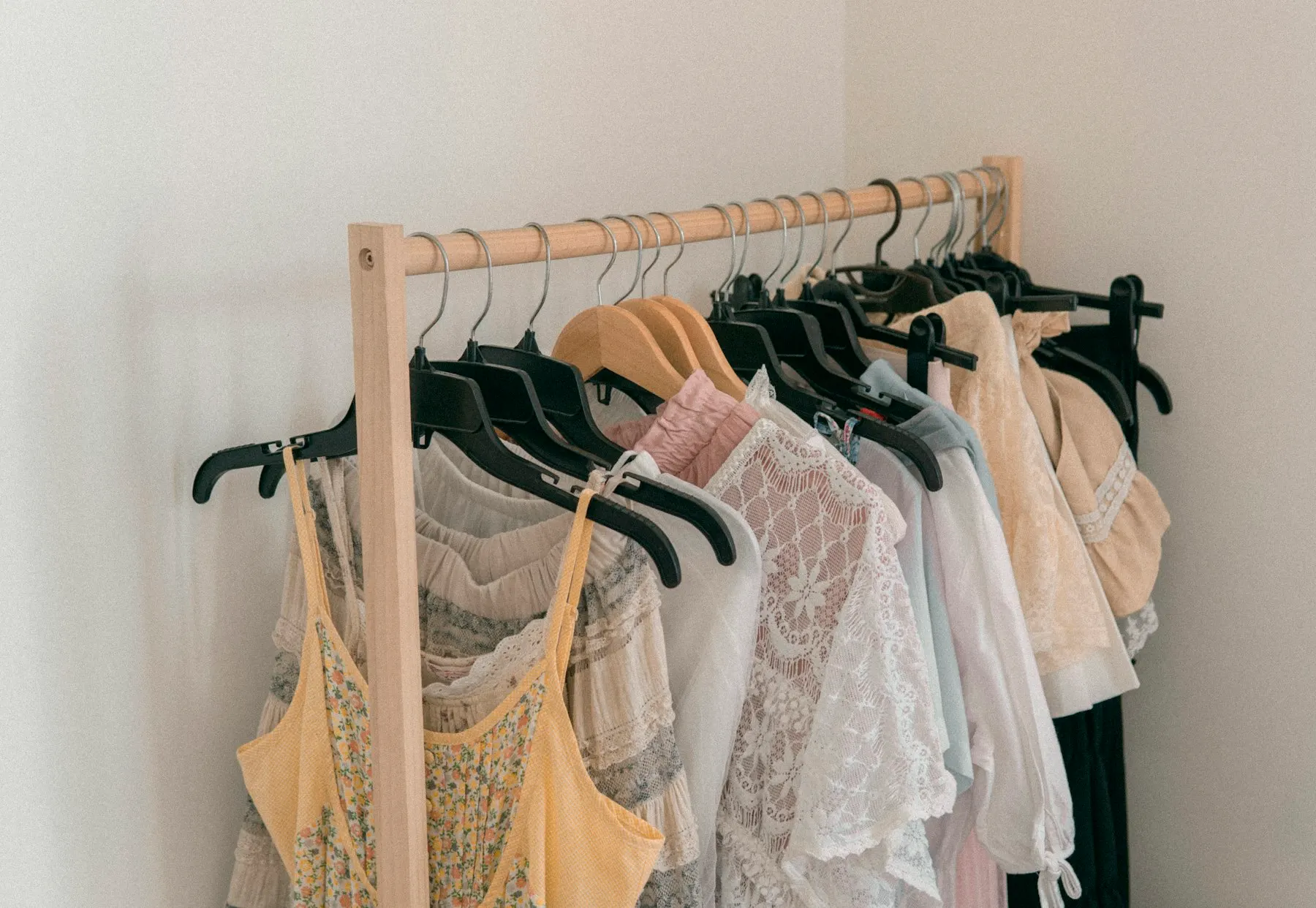 White lace and light-colored tops hanging on a wooden rack
