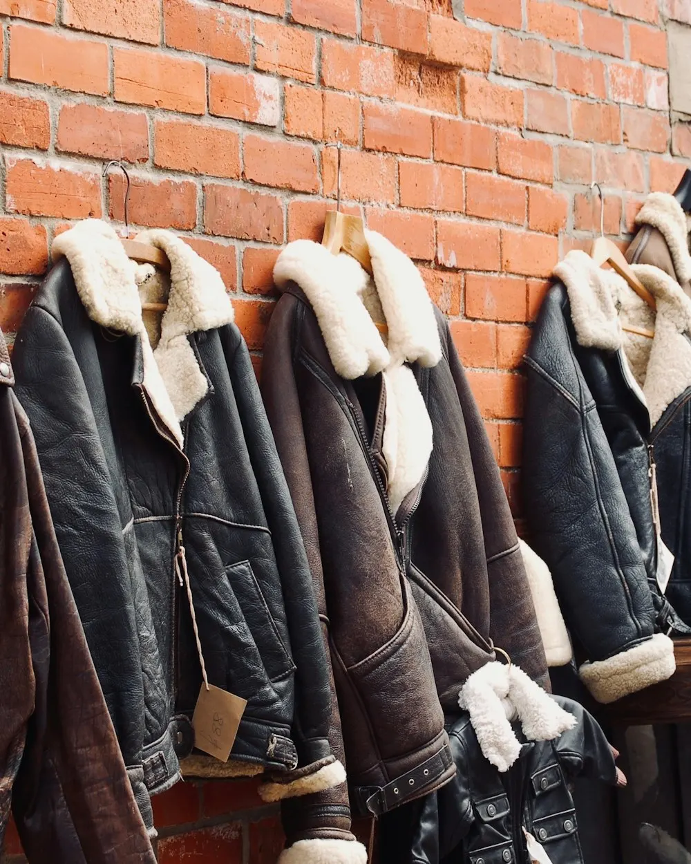 Leather jackets hanging on a rail against brick